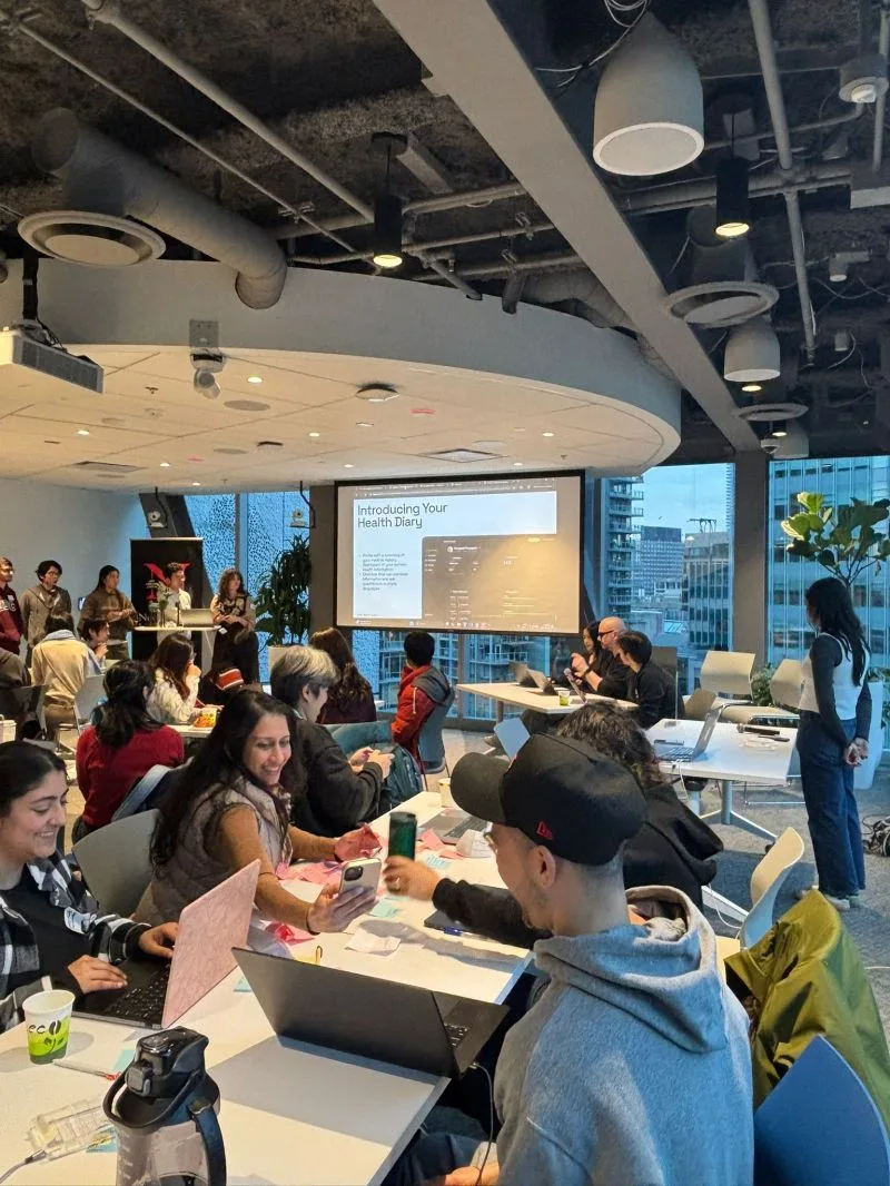 Teams working at tables during the AI Design Hackathon, with a concept slide on the screen